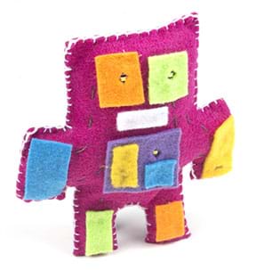 A photograph shows a light-up plush toy made of pink felt with white edge stitching that is shaped with squared off head, arms and legs, and squares of different felt colors added for eyes, hands and feet, as well as to cover the battery holder in the center.