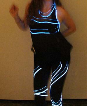 A photograph shows a woman in a black tank top and leggings with glowing lines of blue and white outlining the tank top neckline, around her upper torso and circling around her legs.