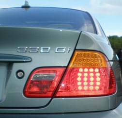 A photograph shows the illuminated LED taillight at the rear passenger-side corner of a sedan car.