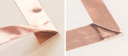 Two photographs: A strip of copper tape is adhered to paper and then at some point it is bent backwards on itself (before being adhered) and then turned at a right angle. Then after folding down to make a square corner (the turn), the copper tape continues being placed in a line on the paper.