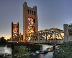 A photograph shows a bridge with two tall towers and a truss structure that provides a roadway across a river.