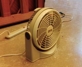 A photograph shows a nine-inch round electric fan resting on a smooth floor.