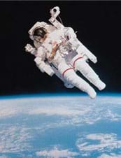 A photograph shows an astronaut in a puffy white suit and glass-faced helmet floating in space with the Earth in the distant background.