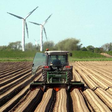 A photograph shows a tractor in a potato field in Germany shaping raised soil rows and using a flame positioned over the soil to kill plants as it goes.