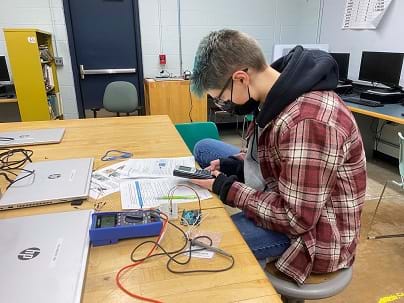 Student is calculating the voltage across resistors in a voltage divider circuit using a graphing calculator.