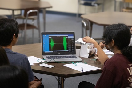 A photo showing students working in a group recording and observing EMG data on their computer in class.