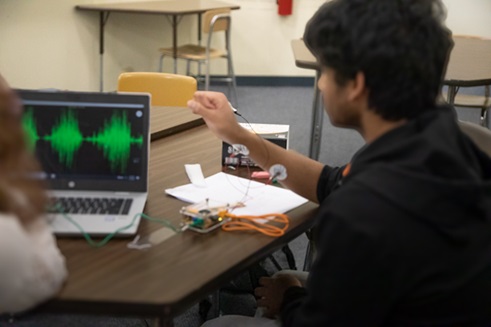 A photo showing students working in a group recording and observing EMG data on their computer in class.