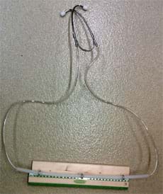 Photo shows a device made from the two metal ear pieces of a stethoscope each attached to clear plastic tubing that runs through metal eyelet screws attached to a piece of wood. 