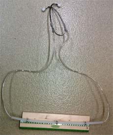 Photo shows a device made from the two metal ear pieces of a stethoscope each attached to clear plastic tubing that runs through metal eyelet screws attached to a piece of wood. 