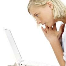 Side-view photo shows a young girl absorbed by what she sees on a laptop monitor screen.