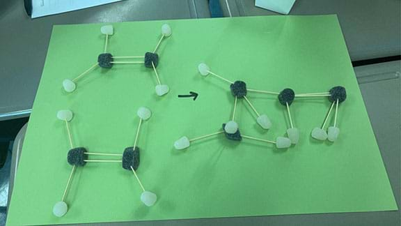 White and black gumdrops are displayed on against a background of green construction paper. The gumdrops are connected by toothpicks to display alkane models.