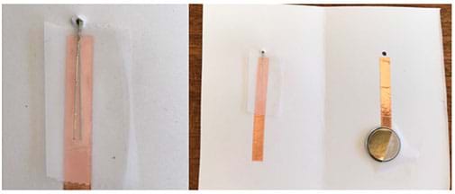 Two photographs. The left shows a closeup of the lefthand side of the card element. A piece of tape facing up has been placed on top of the already taped short wire and the long wire has been pushed down. The right photograph shows the entire card from farther away.  