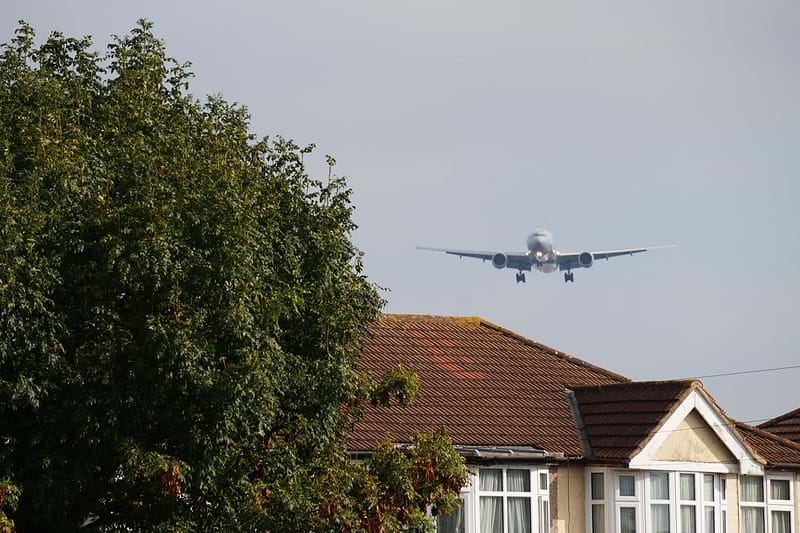 A plane is flying directly above a house.