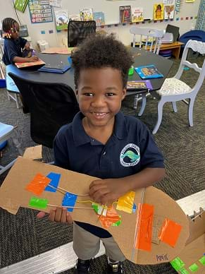 A student holding an instrument design.