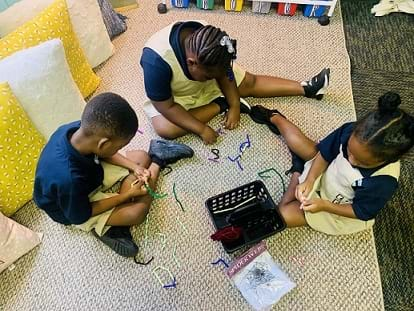 Three students are being observed manipulating straws and chenille sticks/pipe cleaners to create their design.