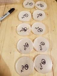 The picture has ten petri dishes of hydrogels each individually labeled with trial numbers. They are sitting on a wood table and there is a sharpie marker on the left-hand side of the picture.