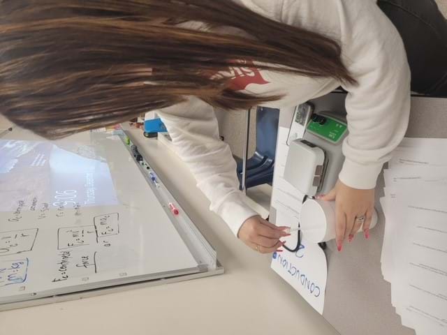 A student uses a hot plate to demonstrate conduction.