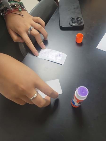 Photo of a student applying glue to two paper strips.