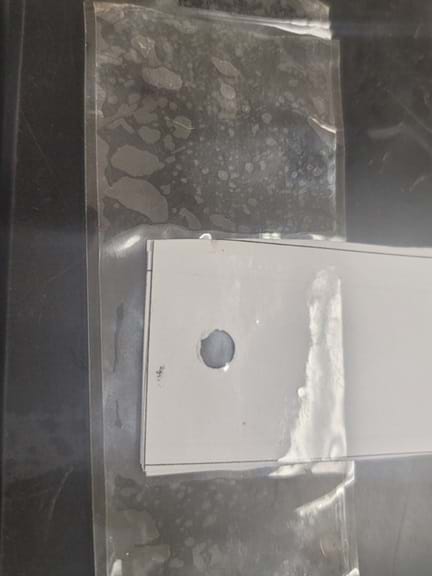 Photo of the top part of a paper strip with a hole punched in it that is reinforced with tape. 