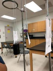 Photo of three hanging paper strips, one of which has a large mass hanging from it. 