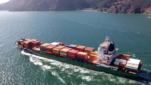 A photograph shows a loaded container ship moving from the San Francisco Bay (CA) towards the Pacific Ocean.