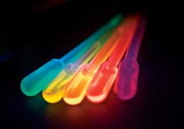 Photo shows five glowing colored vials: blue, yellow, orange, red, violet. Source/Rights: ANL, OSTI Blog, US 