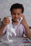 A girl stretches a handful of white gooey material.