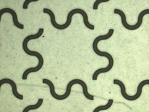 A portion of a mask for a conductor's network print. Looks like black worms on a white sidewalk—a scattering of non-intersecting s-shaped and curved line fragments.