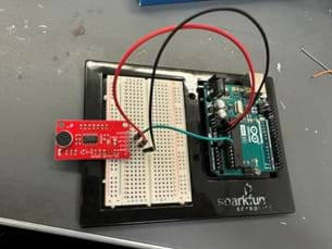A photo of a sound detection circuit built on a breadboard, featuring a red sound detector module connected to an Arduino Uno board, demonstrating basic electronics for noise level measurement.