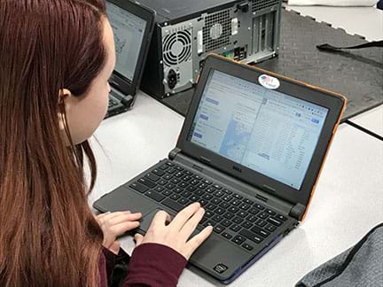 Young female working at a laptop computer converts GPS location to a physical address and records the information into a spreadsheet.