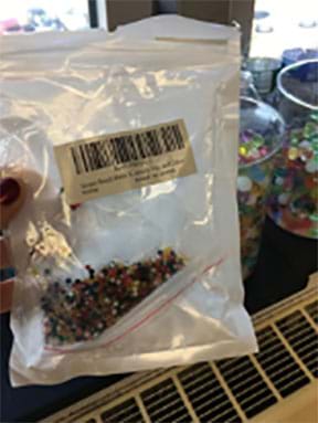 Bag of dehydrated hydrogels with purchasing information in the foreground with rehydrated gels in beakers in the background.