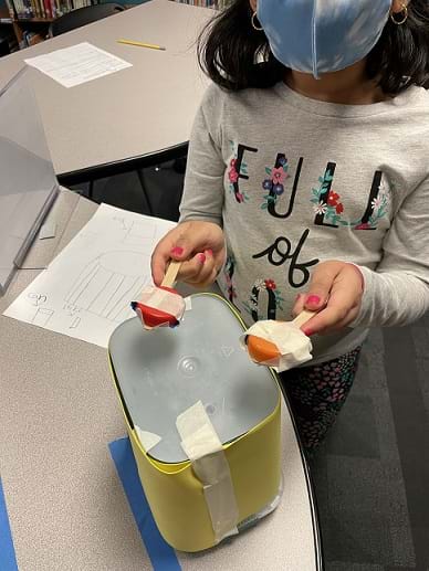 An image of a student’s instrument, drums made from ice cream container, popsicle sticks and bottle caps.