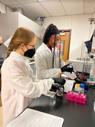 Picture of two college-aged students working in a science lab.