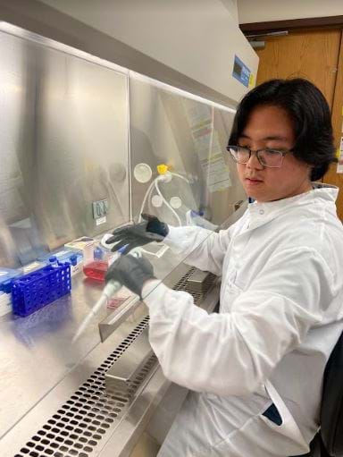 Picture of a college-aged student working in a science lab.