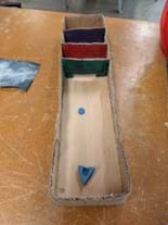 Student prototype with a board that appears not to be modified. Students have used sanding to create a nonuniform surface roughness that is not apparent to the player. The launcher uses a rubber band slingshot mechanism.