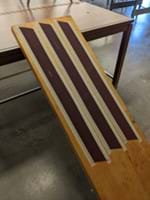 An inclined plane with three long strips of sandpaper of different grits taped to it.