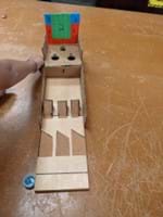 Student prototype with a board modified and three different grits of sandpaper that lead to ramps that lead the puck to three score holes at the back of the board.