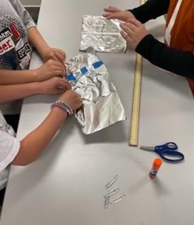 A photo showing three students at a table working on their aluminum rope.