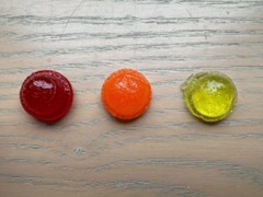 A photo showing a water solution gummy that is red, a sugar solution gummy that is orange, and a salt solution gummy that is yellow.
