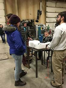 This image shows students and instructors standing around a table putting together their Arduino payloads that will be used to measure cosmic radiation high in the atmosphere.