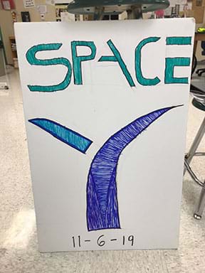 Photograph showing the logo of one of the student space agencies named “Space Y” drawn on a large poster board.