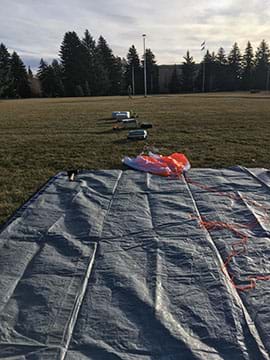 A parachute is attached to the high-altitude balloon to help slow the descent of the payload experiment, high resolution video cameras, and GPS tracking device after the balloon bursts. When attached to the balloon, these items make up the payload train.