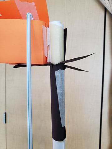 Details of a prototype of a hydroponics system hanging in a classroom. This design is a mock-up using paper materials and plastic straws to simulate a watering system. 
