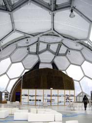A photograph of the interior of the Floating Pavilion in Rotterdam, Netherlands, shows a transparent plastic geodesic dome structure enclosing an exhibit space.