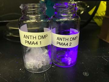 Photograph of two poly(methylacrylate) samples. The left sample is white; the right sample has fluorescent anthracene tag and appears purple. 