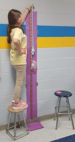 Photograph of student Sierra Graham determining the optimum stretching speed of slime using a tensile strength test.