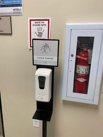 Hand sanitizer and wall signage in a school during the COVID-19 pandemic.