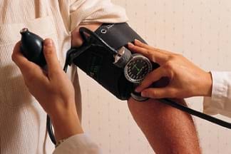 Photo shows a person's blood pressure reading being taken with a cuff and stethoscope.