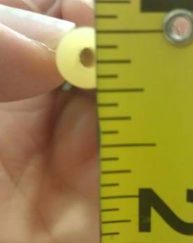 A close-up photograph shows a hand holding the cross-section end of a latex tube (looks like a lifesaver mint candy from this angle) next to the lines on a measuring ruler.