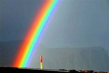 Enhanced photo shows a very bright rainbow against a dark gray sky.